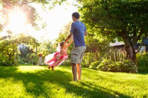 dad-swinging-daughter-on-grass